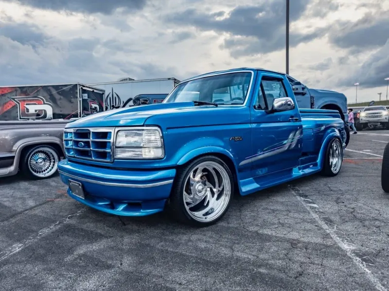 Blue Ford Flareside pickup with pinstripe graphics parked at a Texas car show