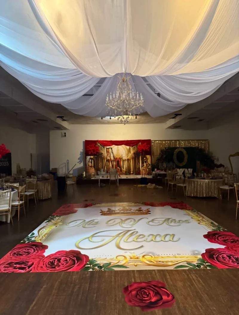 White and gold dance floor wrap reading Mis XV Anos Alexa framed with red roses