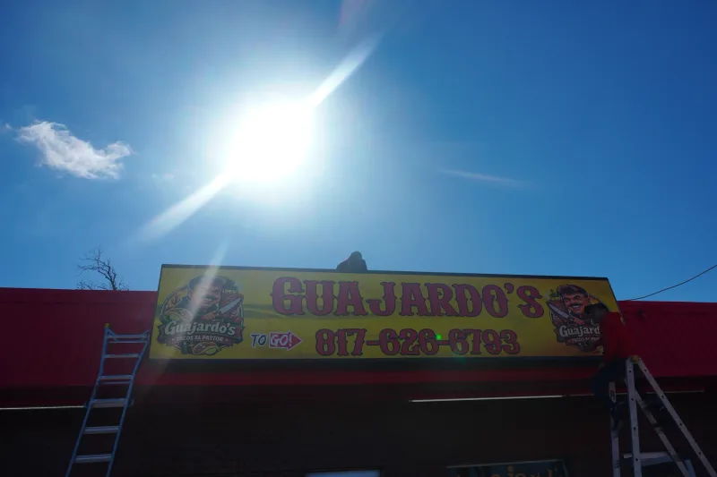 Freshly installed Guajardo's storefront sign shot against the Texas sun