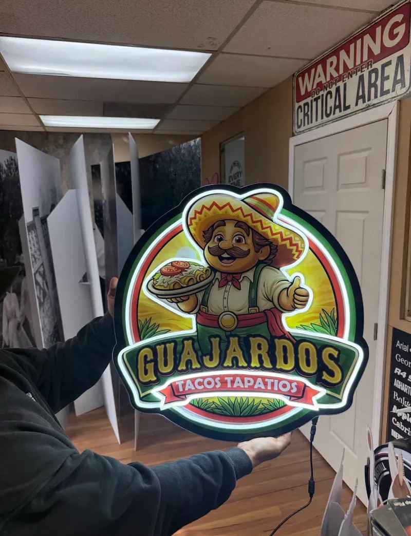Backlit shaped sign of the Guajardos Tacos Tapatios logo held up in the shop