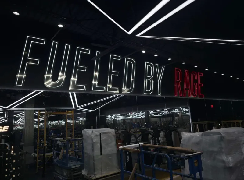 Large LED neon sign reading Fueled By Rage hanging inside a gym