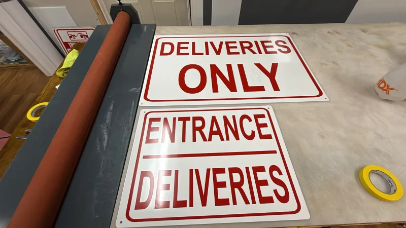 Two printed aluminum signs reading Deliveries Only and Entrance Deliveries