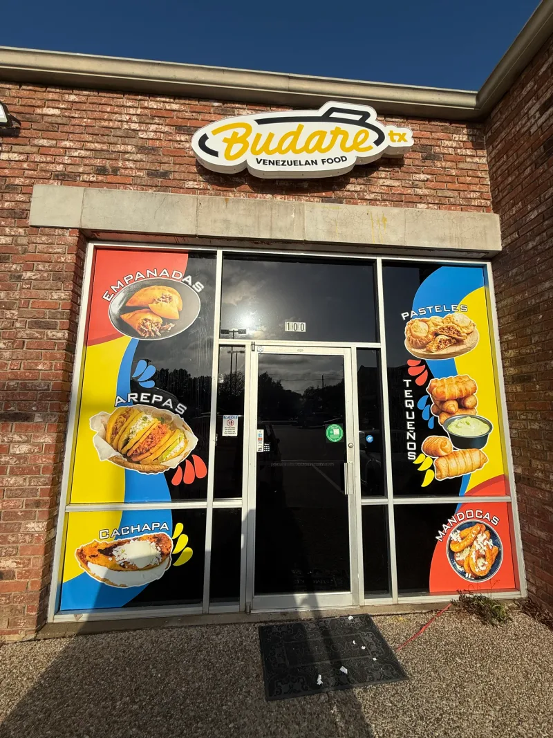 Venezuelan restaurant storefront with shaped sign and printed window graphics of the menu