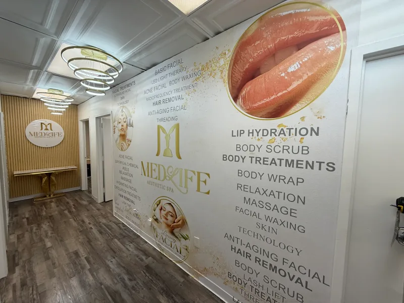 Aesthetic spa hallway with a full printed wall mural listing treatments in gold and grey